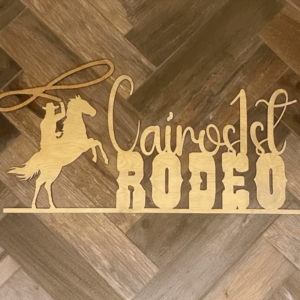 Cairo's 1st Rodeo wooden sign features a silhouetted cowboy on a horse, emphasizing the event's western theme. Ideal for promoting the rodeo.