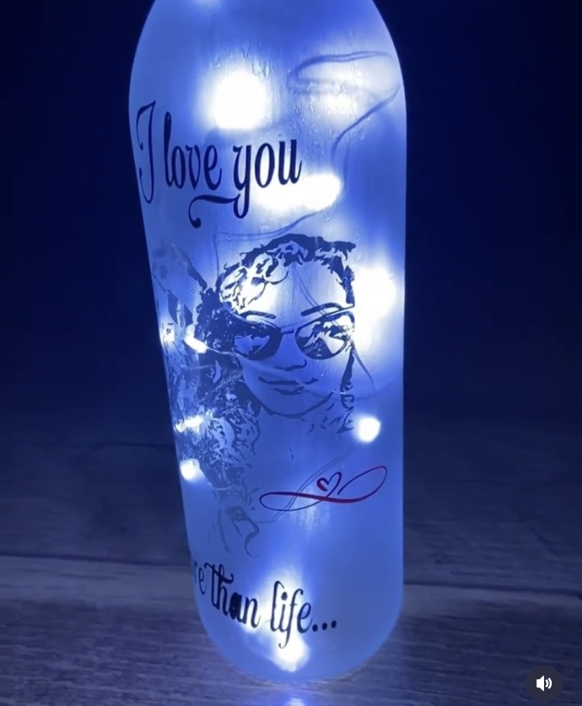 Decorative bottle with a glowing interior, featuring a design that reads "I love you more than life," alongside a playful illustration.