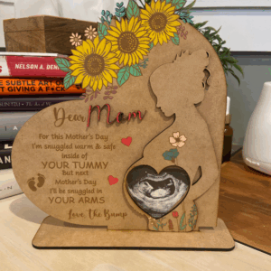 A heart-shaped plaque for Mother's Day, featuring a silhouette of a pregnant woman, flowers, and a sonogram image, celebrating maternal love and upcoming motherhood.